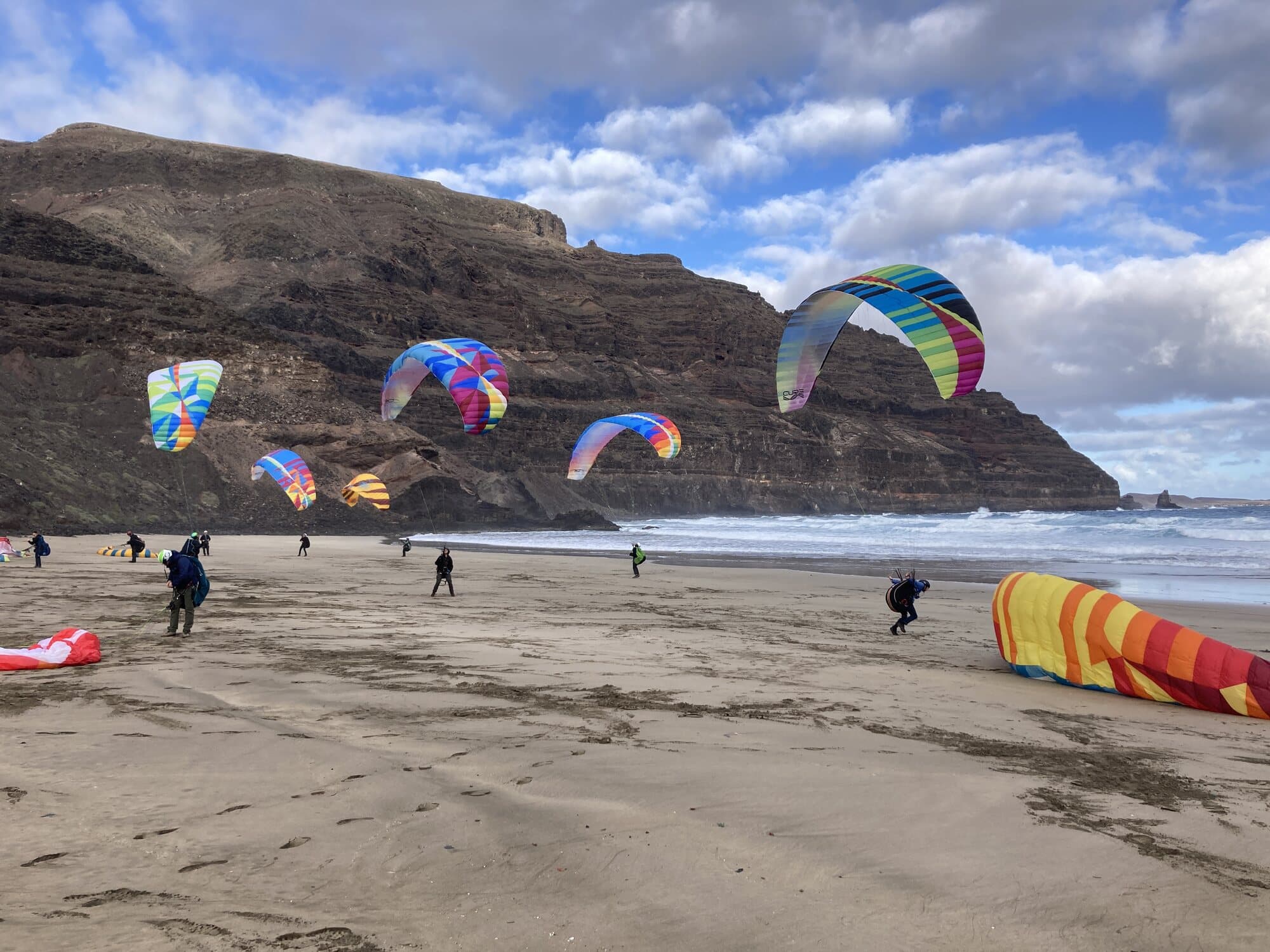 Paraglider pilots ground handling on Famara beach under the cliffs